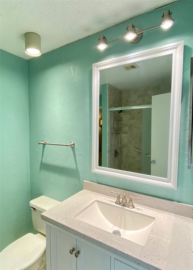 bathroom featuring a textured ceiling, vanity, toilet, and an enclosed shower