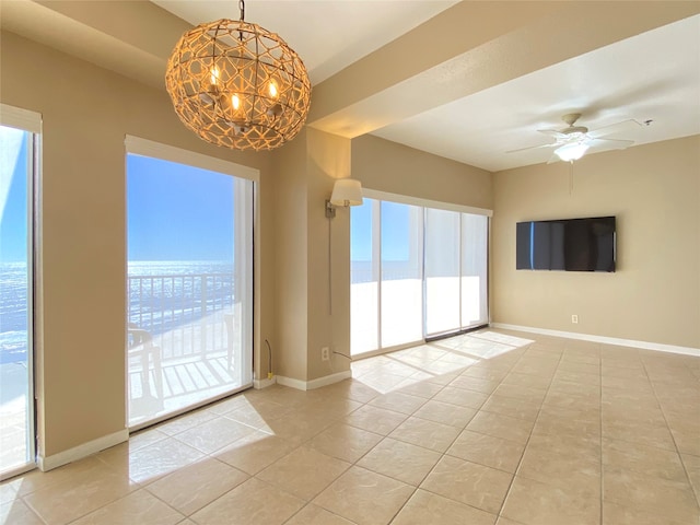 tiled spare room with ceiling fan with notable chandelier