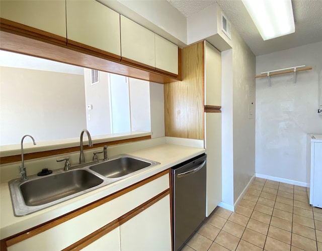 kitchen featuring light tile patterned floors, a textured ceiling, stainless steel dishwasher, and sink