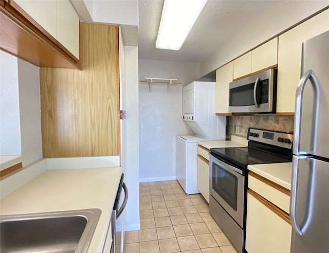 kitchen featuring backsplash, white cabinets, light tile patterned floors, a textured ceiling, and stainless steel appliances