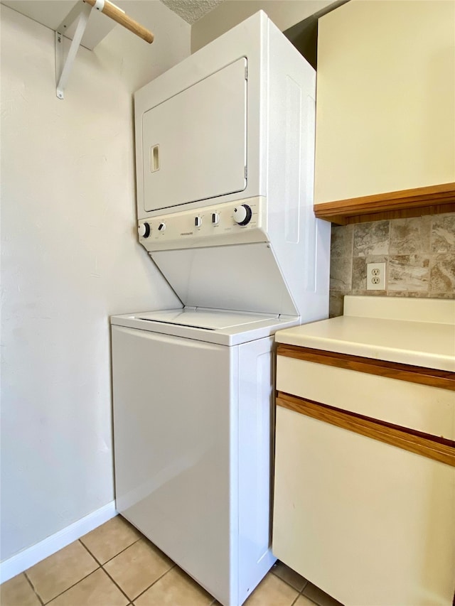 washroom with stacked washer / dryer and light tile patterned floors