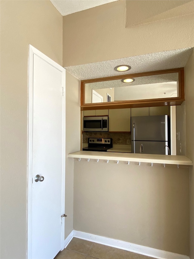 kitchen featuring appliances with stainless steel finishes, a textured ceiling, tile patterned floors, and sink