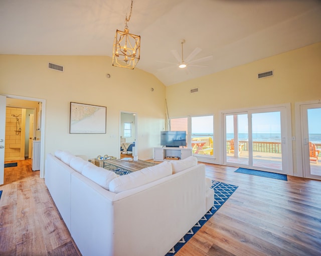 living room featuring high vaulted ceiling, ceiling fan with notable chandelier, and light hardwood / wood-style flooring