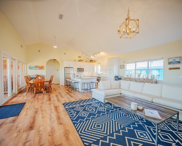 living room featuring hardwood / wood-style floors, ceiling fan with notable chandelier, and high vaulted ceiling