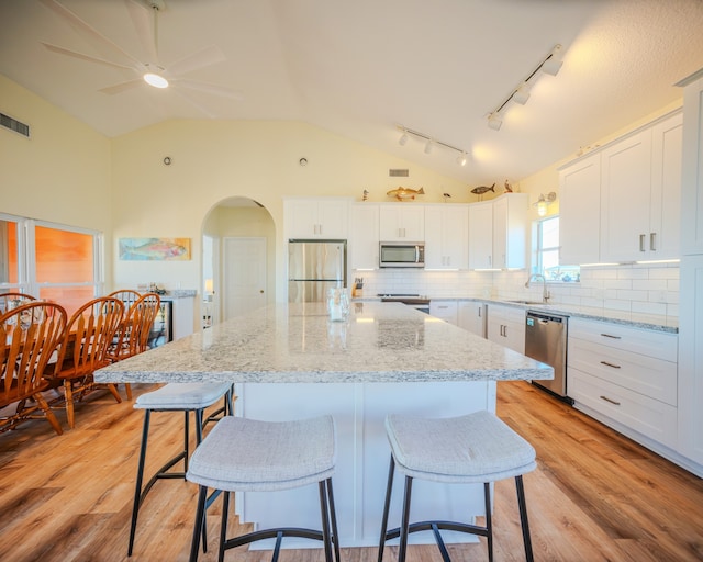 kitchen featuring stainless steel appliances, white cabinets, light wood-type flooring, and a kitchen island