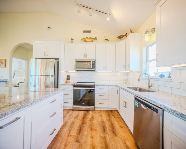 kitchen with white cabinetry, appliances with stainless steel finishes, light wood-type flooring, sink, and lofted ceiling