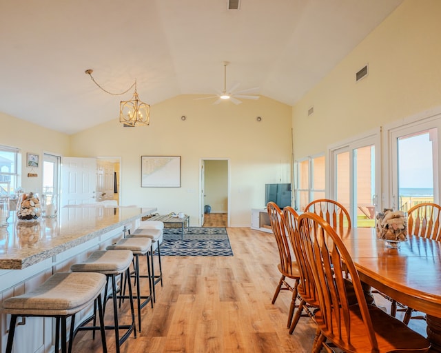 dining room with high vaulted ceiling, light hardwood / wood-style floors, and ceiling fan with notable chandelier