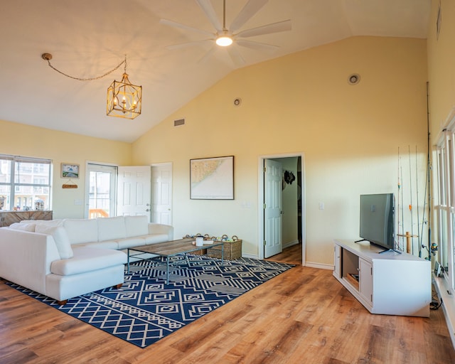 living room with high vaulted ceiling, light hardwood / wood-style flooring, and ceiling fan with notable chandelier