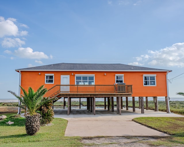 back of property featuring a deck, a lawn, and a carport