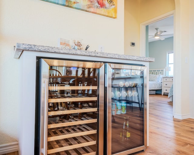 wine cellar with wood-type flooring, indoor bar, and ceiling fan