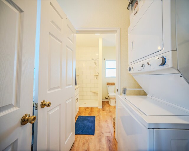 laundry room with stacked washing maching and dryer and light wood-type flooring