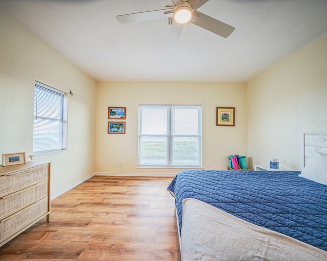 bedroom with light hardwood / wood-style floors, ceiling fan, and multiple windows