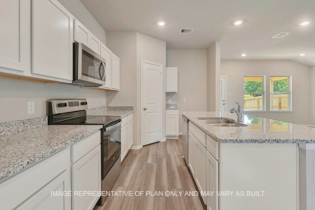 kitchen featuring stainless steel appliances, white cabinetry, sink, a center island with sink, and light hardwood / wood-style flooring