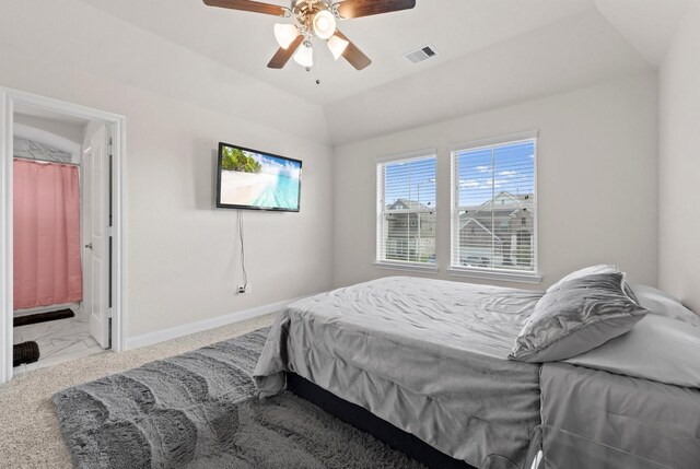 bedroom featuring ceiling fan, connected bathroom, lofted ceiling, and light colored carpet