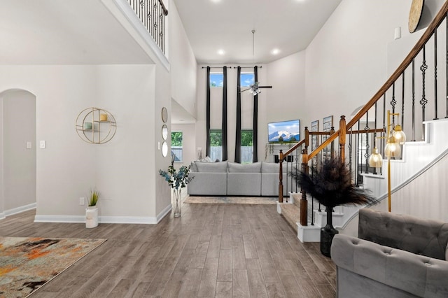 foyer entrance with hardwood / wood-style flooring, a high ceiling, and ceiling fan