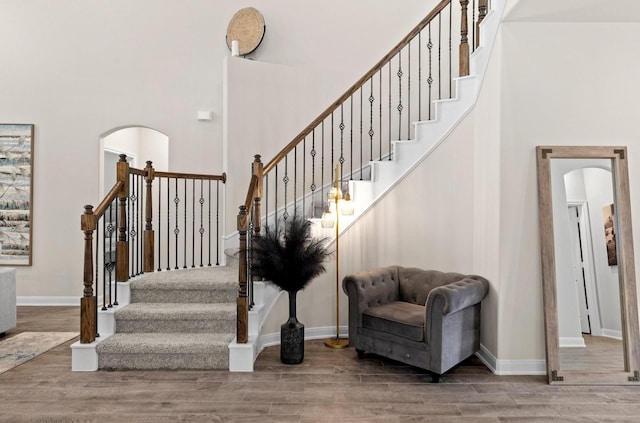 stairs featuring hardwood / wood-style floors and a towering ceiling