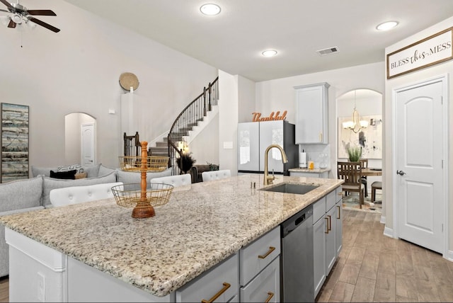 kitchen with light stone countertops, sink, light hardwood / wood-style floors, stainless steel dishwasher, and a kitchen island with sink