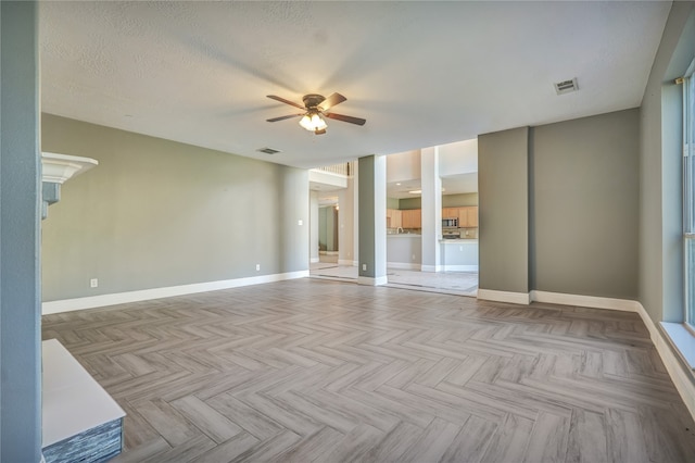 unfurnished room featuring ceiling fan, light parquet flooring, and a textured ceiling