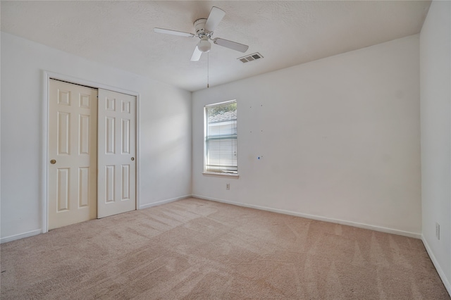 unfurnished bedroom with ceiling fan, light colored carpet, and a closet