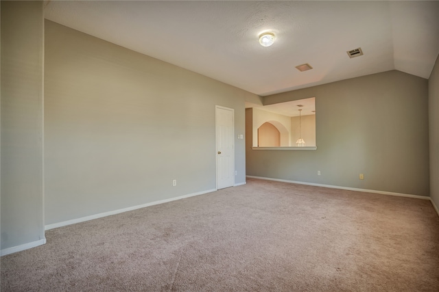 spare room featuring carpet floors and vaulted ceiling