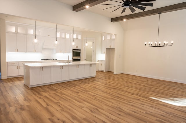 kitchen with pendant lighting, ceiling fan, white cabinetry, and an island with sink