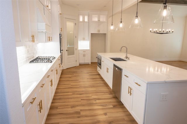 kitchen with sink, premium range hood, a center island with sink, white cabinets, and appliances with stainless steel finishes