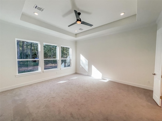 empty room with light carpet, a raised ceiling, ceiling fan, and crown molding