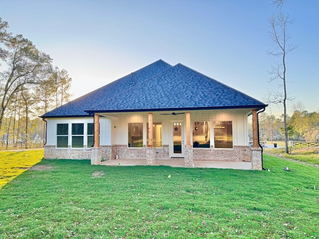 rear view of property with ceiling fan and a yard