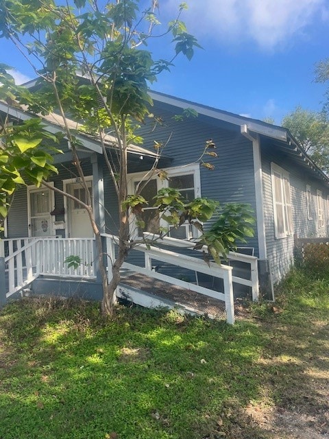 view of side of home featuring a lawn and covered porch