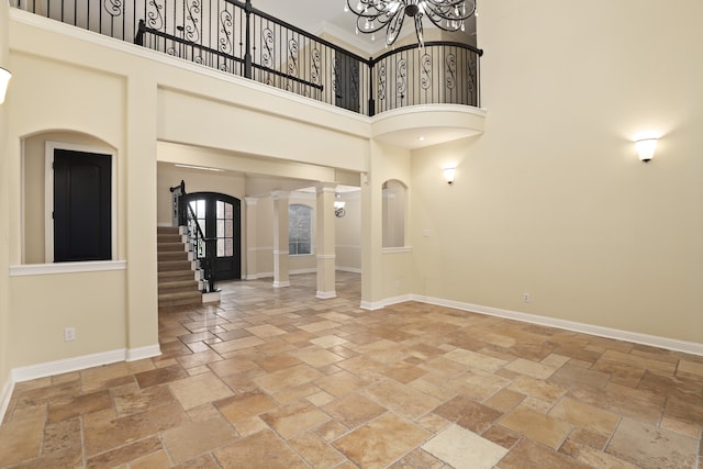 foyer entrance with decorative columns, an inviting chandelier, and a towering ceiling