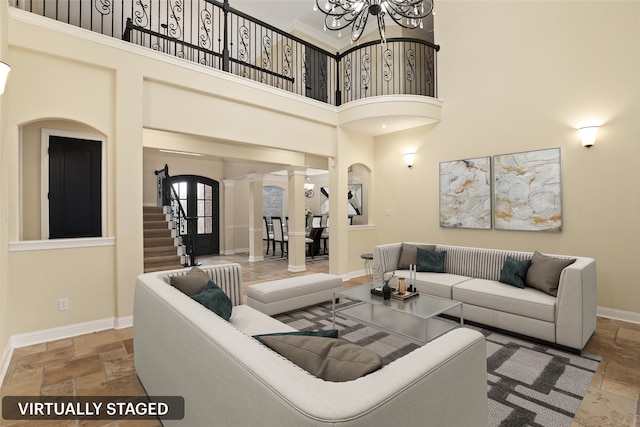 living room featuring ornate columns, a towering ceiling, and a notable chandelier