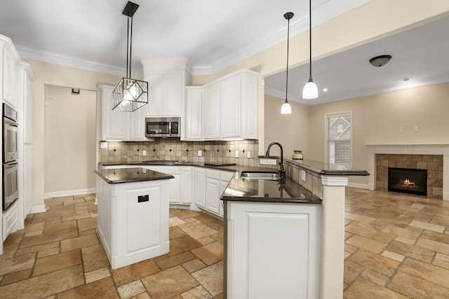 kitchen with appliances with stainless steel finishes, sink, decorative light fixtures, and kitchen peninsula