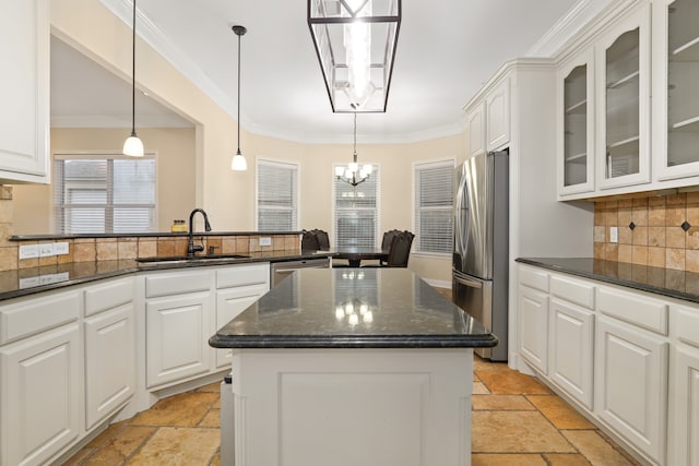 kitchen featuring sink, appliances with stainless steel finishes, backsplash, a kitchen island, and white cabinets