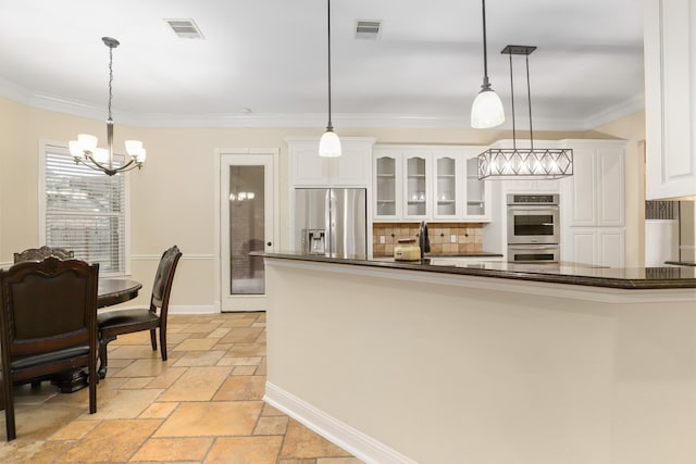 kitchen with white cabinets, decorative light fixtures, crown molding, and stainless steel appliances