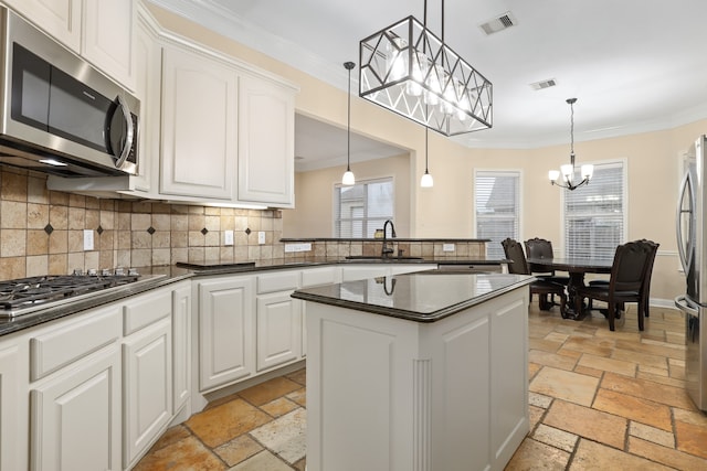 kitchen with white cabinets, appliances with stainless steel finishes, and decorative light fixtures