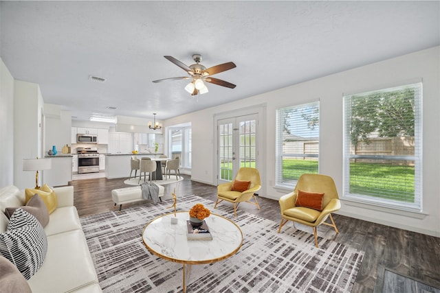 living room featuring dark wood-type flooring, ceiling fan with notable chandelier, and a textured ceiling