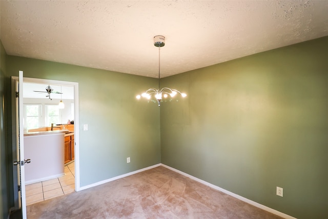 carpeted empty room with a textured ceiling and ceiling fan with notable chandelier