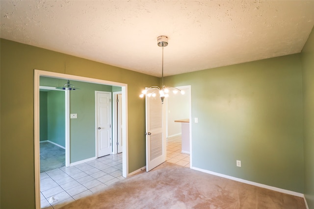 carpeted empty room featuring a textured ceiling and an inviting chandelier