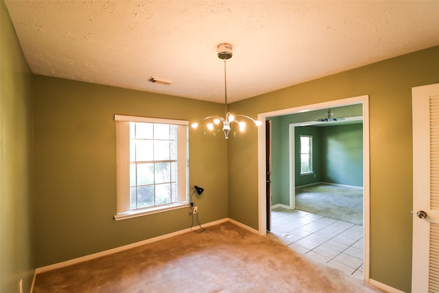 spare room featuring light carpet and a textured ceiling