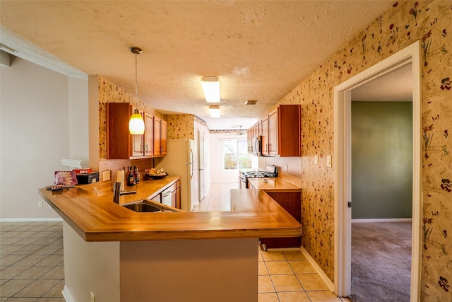 kitchen featuring kitchen peninsula, appliances with stainless steel finishes, a textured ceiling, and decorative light fixtures