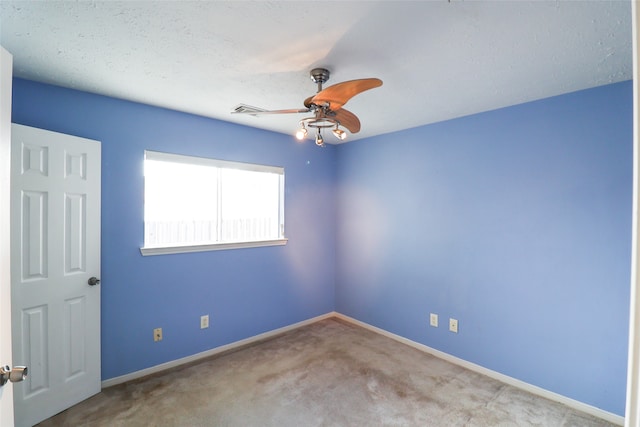 spare room featuring a textured ceiling, light colored carpet, and ceiling fan