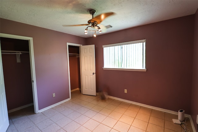 unfurnished bedroom with ceiling fan, light tile patterned flooring, and a textured ceiling