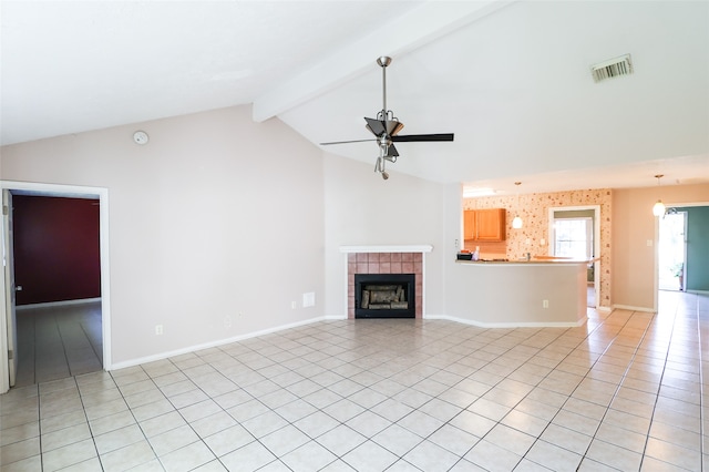 unfurnished living room with light tile patterned floors, vaulted ceiling with beams, ceiling fan, and a tiled fireplace