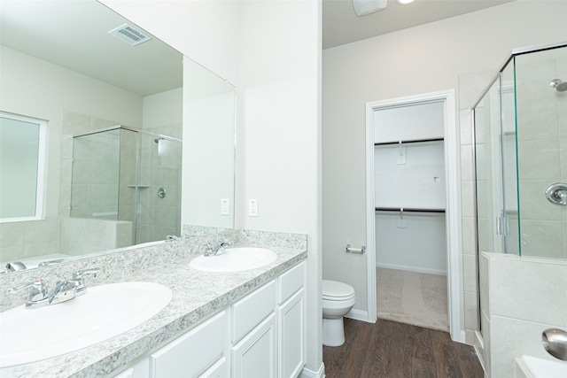 bathroom with hardwood / wood-style floors, vanity, toilet, and a shower with door