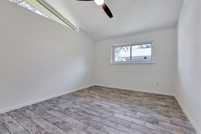 empty room with ceiling fan, light hardwood / wood-style floors, and vaulted ceiling