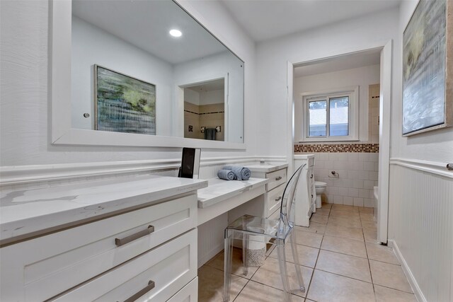 bathroom with tile patterned floors, vanity, tile walls, and toilet