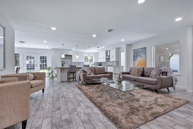 living room with plenty of natural light, light hardwood / wood-style floors, and french doors