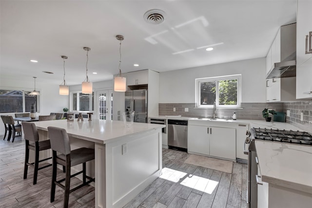 kitchen with pendant lighting, white cabinets, stainless steel appliances, and a kitchen island