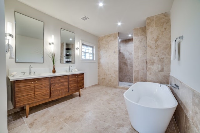 bathroom featuring independent shower and bath, vanity, and tile walls