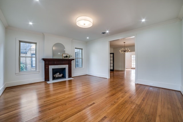 unfurnished living room featuring ornamental molding, hardwood / wood-style floors, a tile fireplace, and an inviting chandelier